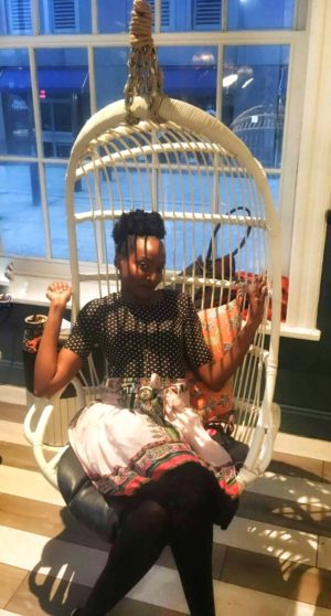Black girl in bamboo egg chair at Seaport District New York City