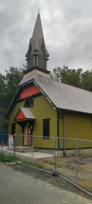 Church with yellow and red facade with small steeple, in Auburn, NY, under renovation.