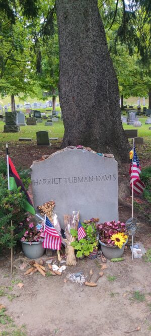 Grave site with the name Harriet Tubman Davis written on it surrounded by U.S. flags, badges, and flowers.