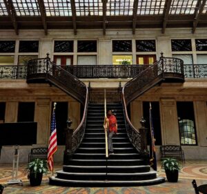 Black woman posing on a grand staircase in an atrium in Buffalo on a weekend getaway.